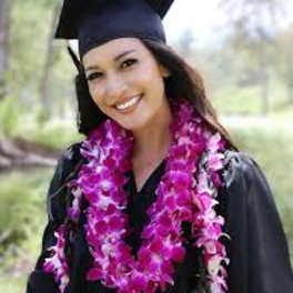 Graduate in cap and gown wearing a pink flower lei