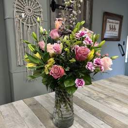 Mixed pink and yellow flowers arranged in a clear glass vase