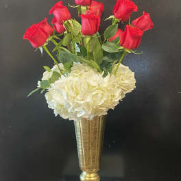 Red roses above white hydrangeas in a gold vase