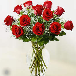 Red roses arranged in a clear glass vase with baby's breath