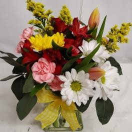 Mixed bouquet in a glass vase with daisies, tulips, carnations, and red blooms