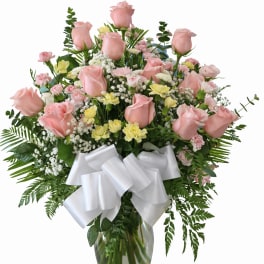 Pink roses and mixed flowers in a glass vase with a white bow