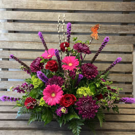 Bright mixed flower arrangement with roses, gerbera daisies, and purple blooms