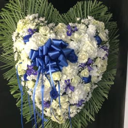 Heart-shaped floral wreath with white and blue flowers and a blue ribbon bow