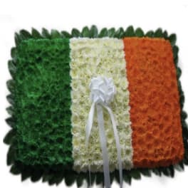 Floral tribute in green, white, and orange with a white ribbon bow