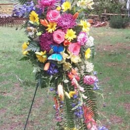 Tall standing floral spray with mixed bright flowers on a metal easel