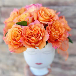 Orange roses arranged in a white vase