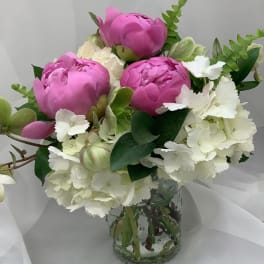 Pink peonies and white hydrangeas in a clear glass vase