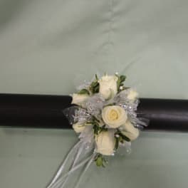 White rose corsage with silver ribbon on a black cylindrical box