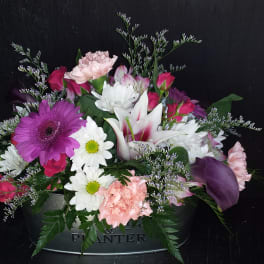 Mixed bouquet in a metal planter with pink, white, and purple flowers