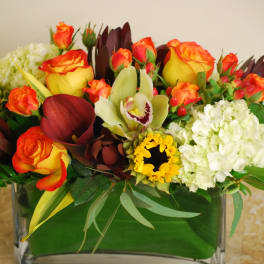 Mixed floral arrangement in a glass vase with orange roses and white hydrangeas