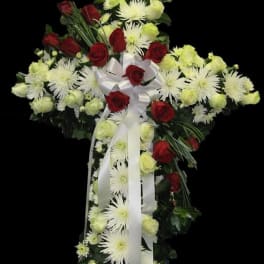 Cross-shaped floral spray with red roses, white chrysanthemums, and white ribbon