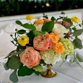 Peach and white floral arrangement in a gold vase