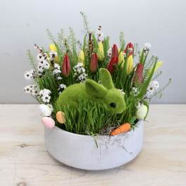 Spring arrangement with tulips and a moss bunny in a round planter