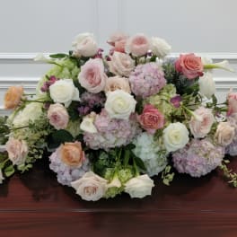 Large pastel floral arrangement with roses and hydrangeas on a polished table
