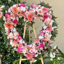 Heart-shaped floral wreath on an easel with pink and white flowers