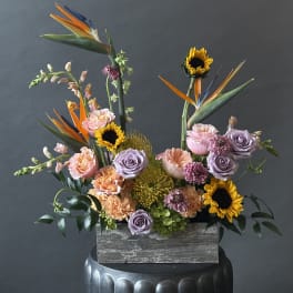 Mixed bouquet with sunflowers, roses, and bird of paradise in a wooden box