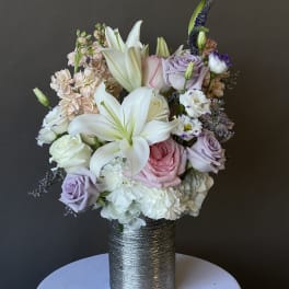 Pastel bouquet of lilies, roses, and carnations in a silver vase