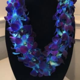 Purple and blue orchid lei on a black display bust