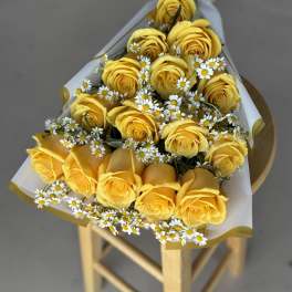 Bouquet of yellow roses with small white daisies wrapped in white paper