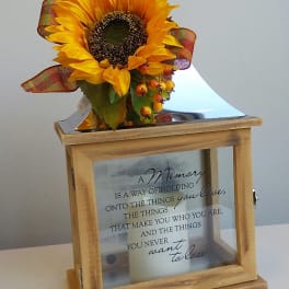 Sunflower arrangement on a wooden memorial box with a candle inside