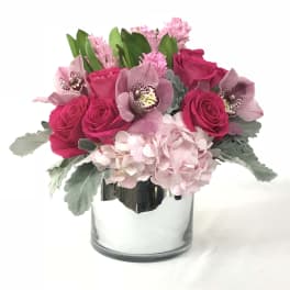 Pink roses and orchids arranged in a clear glass vase