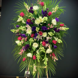 Large standing floral spray with pink roses, white blooms, and purple flowers