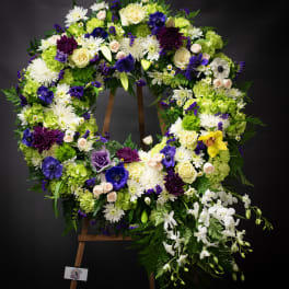 Large floral wreath on an easel with white, purple, and green flowers