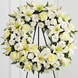 White wreath of lilies, roses, and chrysanthemums on a metal easel stand