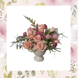 Pink roses and tulips arranged in a white pedestal vase