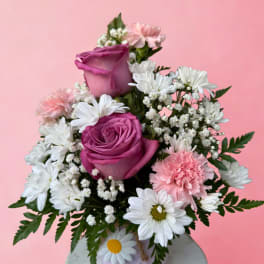 Pink and white bouquet with roses, daisies, and carnations in a small vase