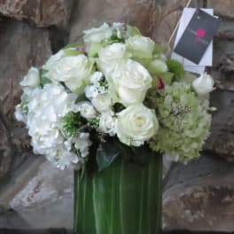 White roses and hydrangeas arranged in a tall green vase