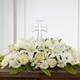White floral casket spray with a clear cross centerpiece
