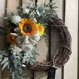 Floral wreath with sunflowers and white blooms on a grapevine ring