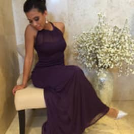 Woman in a purple dress seated beside a vase of white baby's breath
