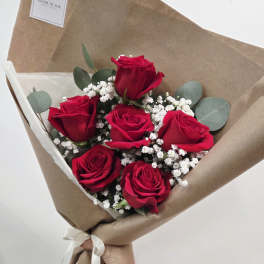Bouquet of red roses with white baby's breath wrapped in brown paper