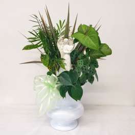 Green plant arrangement in a white vase with a small angel figurine