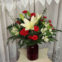Red carnations and white lilies in a burgundy vase