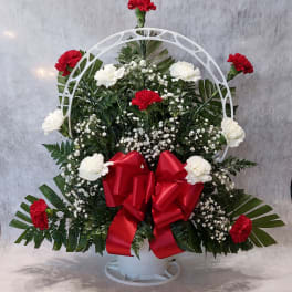 Standing floral wreath with red and white carnations and a red bow