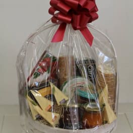 Gourmet gift basket wrapped in clear cellophane with a large red bow on top