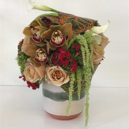 Bouquet of beige roses, orchids, and calla lilies in a ceramic vase