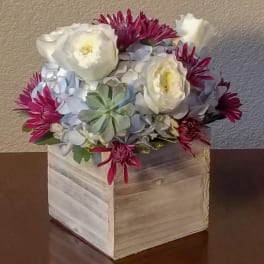 White and magenta flowers arranged in a square wooden box