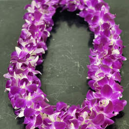 Purple orchid lei on a dark surface