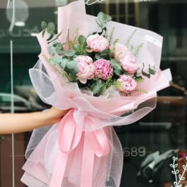 Pink peony bouquet wrapped in pale pink paper and tulle
