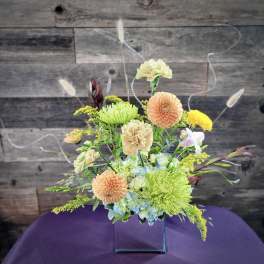Mixed pastel flower arrangement in a clear square vase