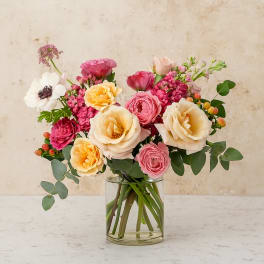 Mixed pink and cream flowers arranged in a clear glass vase