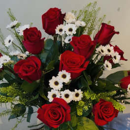 Bouquet of red roses mixed with small white daisies against a neutral background