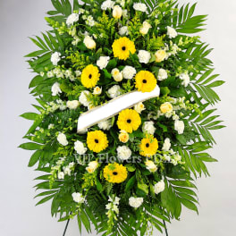 Standing funeral wreath of yellow and white flowers on an easel