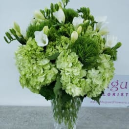 Green and white floral arrangement in a clear glass vase
