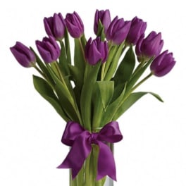 Purple tulips in a clear glass vase tied with a purple ribbon